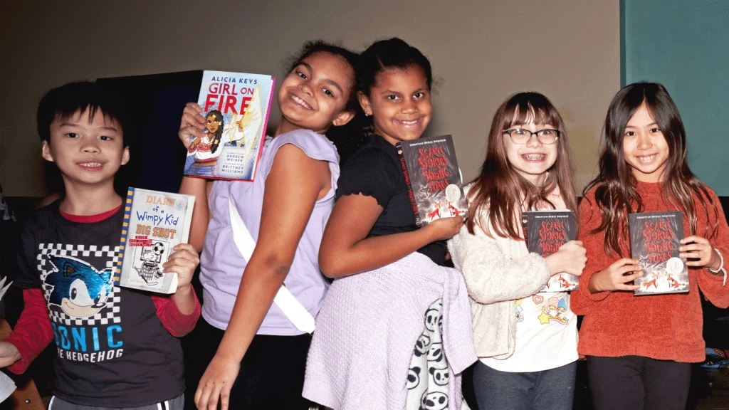Children holding books and smiling